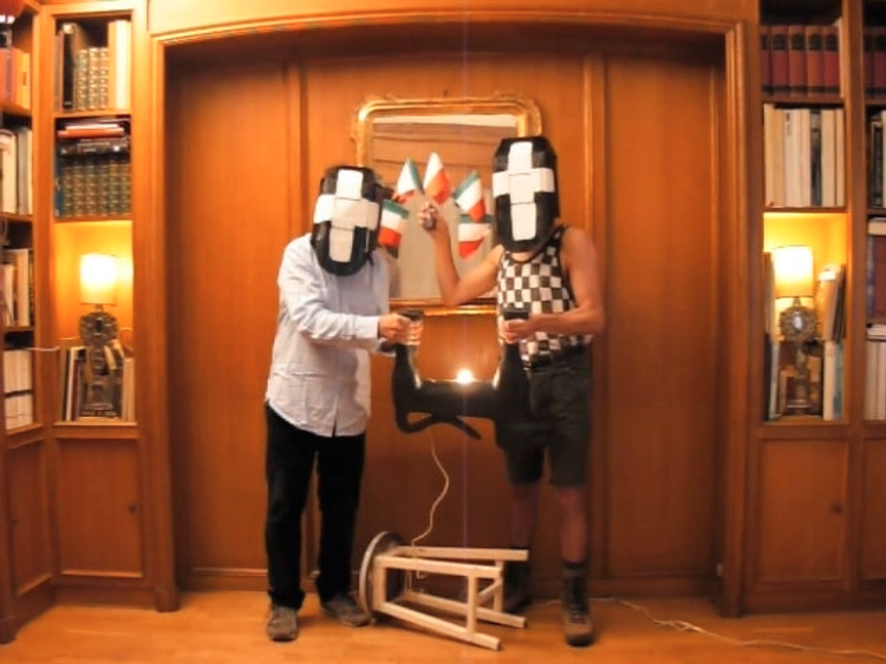 ein Bild aus einem Videofilm mit zwei maskierten Personen, die eine Hundeskulptur halten