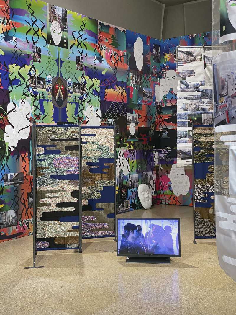 eine raumgreifende Installation aus bunten Tapeten und Raumteilern mit japanischen Motiven, dazwischen Bildschirme mit Videos
