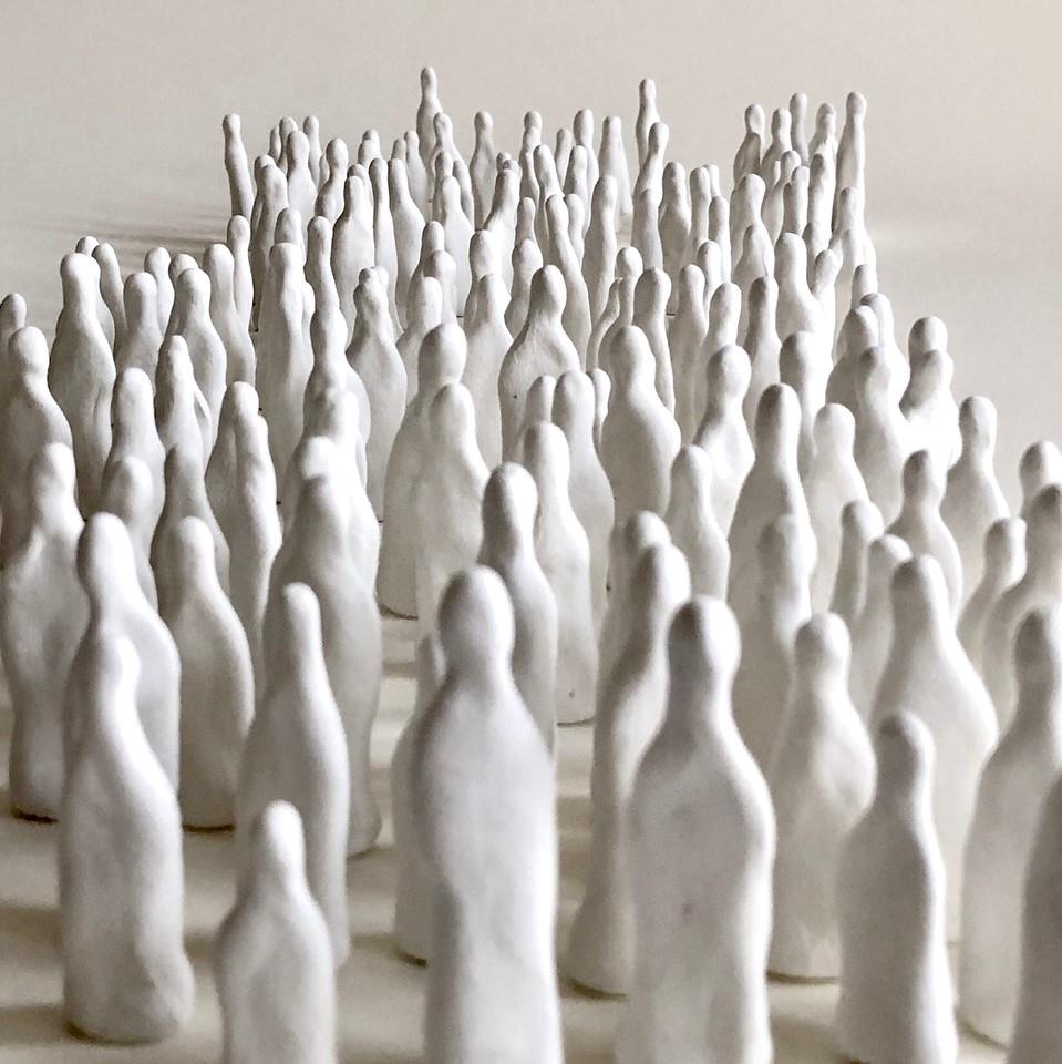 eine große Gruppe weißer, abstrakter Miniaturfiguren auf hellem Untergrund