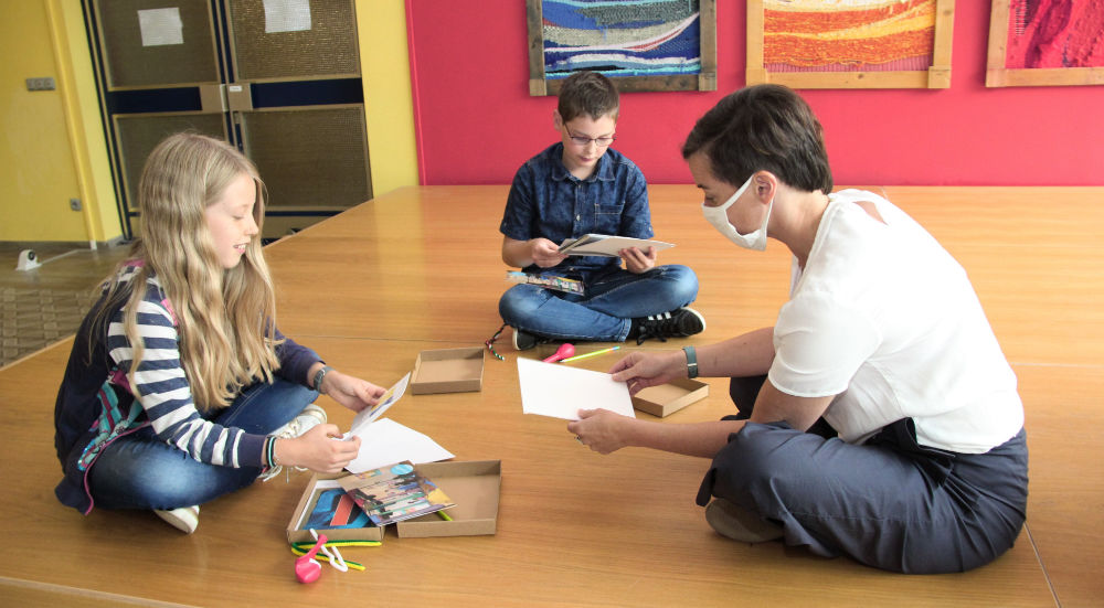 Kinder sitzen auf dem Fußboden beim Auspacken der Kunstkisten