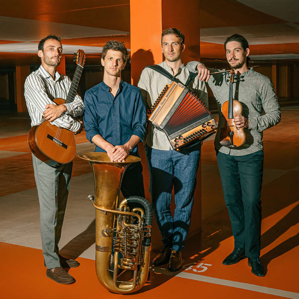 vier Musiker mit Gitarre, Horn, Akkordeon und Geige
