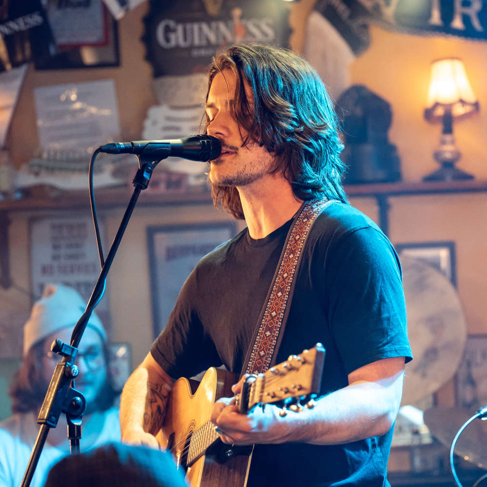 Ein Mann mit Gitarre singt in ein Mikrofon
