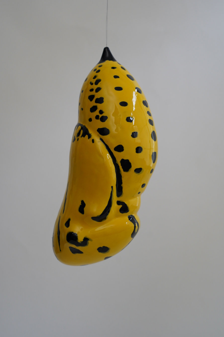 eine gelbe Keramik-Skulptur mit schwarzen Flecken, die von der Decke hängte