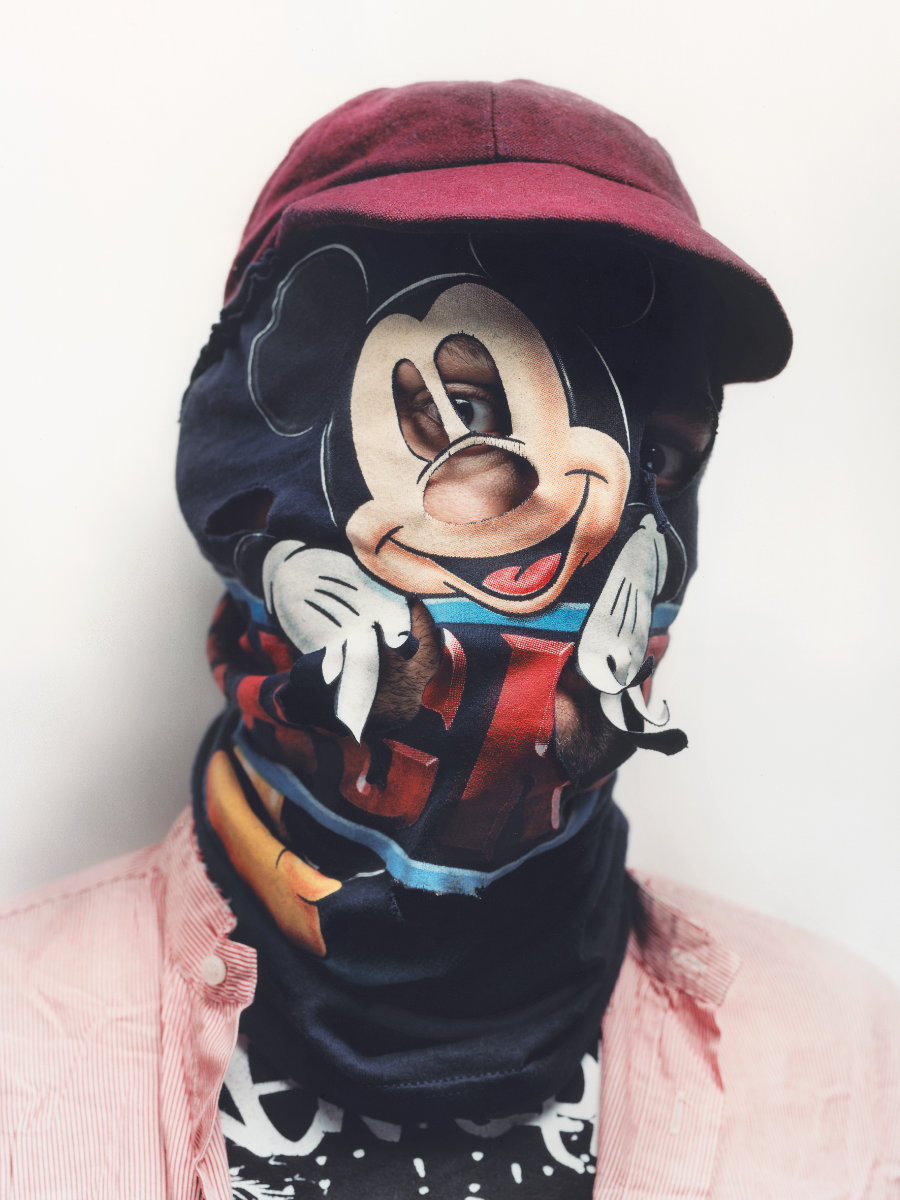 Fotografie einer Person, die eine Stoffhaube mit einem Mickey-Mouse Motiv über dem Gesicht trägt