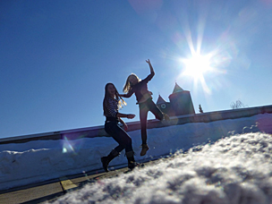 zwei Personen springen vor sonnigem Himmel in die Luft